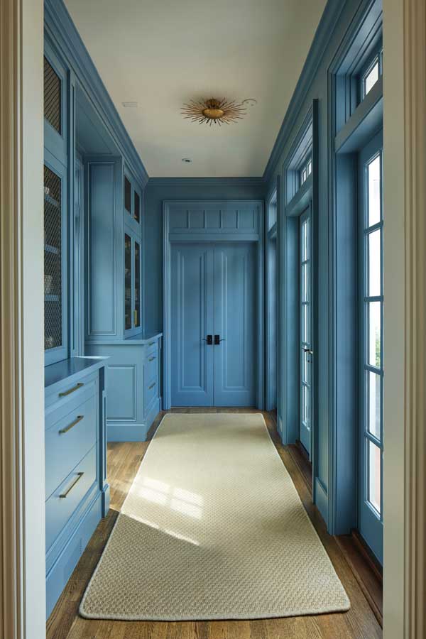 Camera facing a door at the end of hallway with blue walls and wooden floor